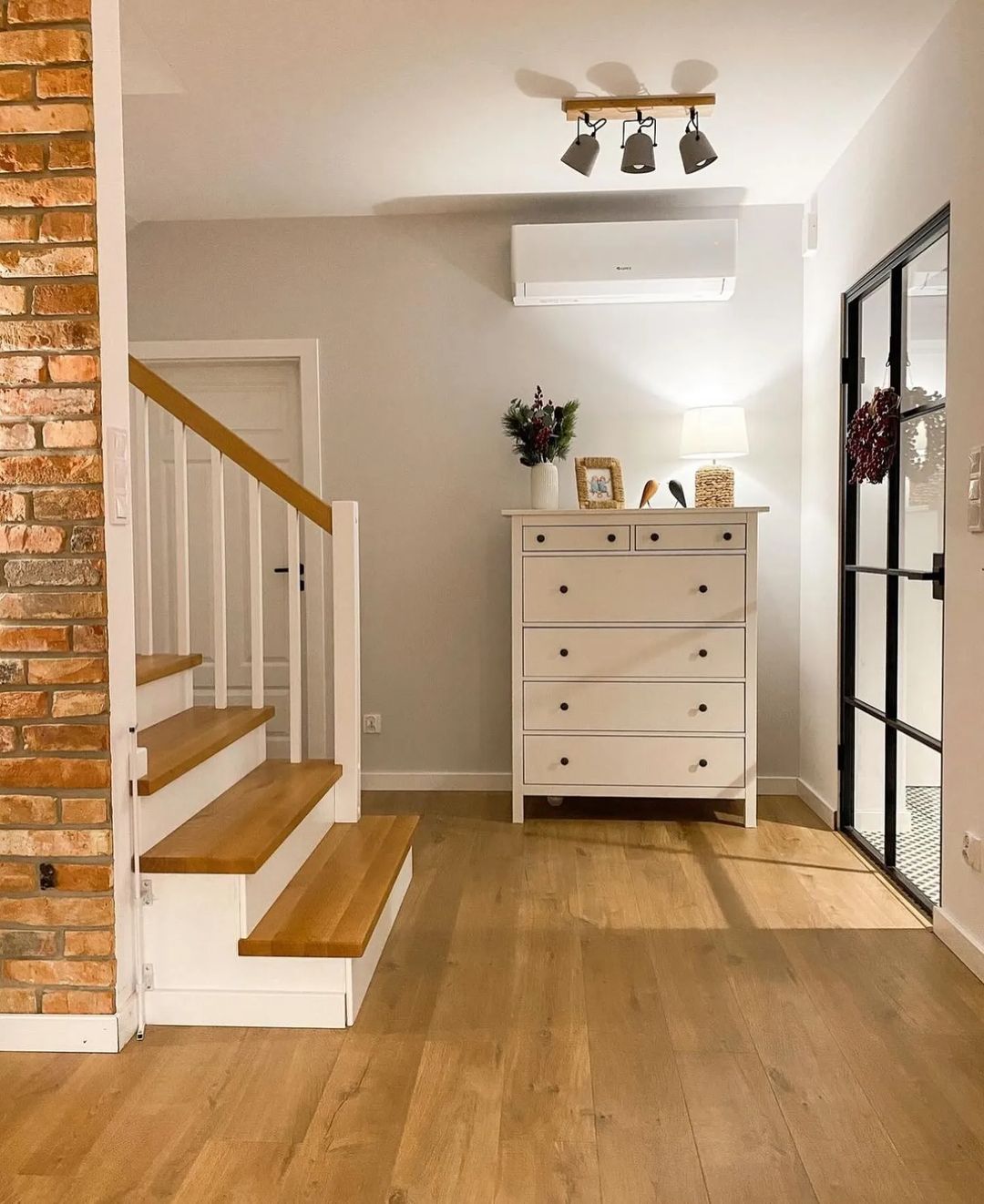 Stylish modern hallway featuring a blend of textures with exposed brick and sleek white furnishings.