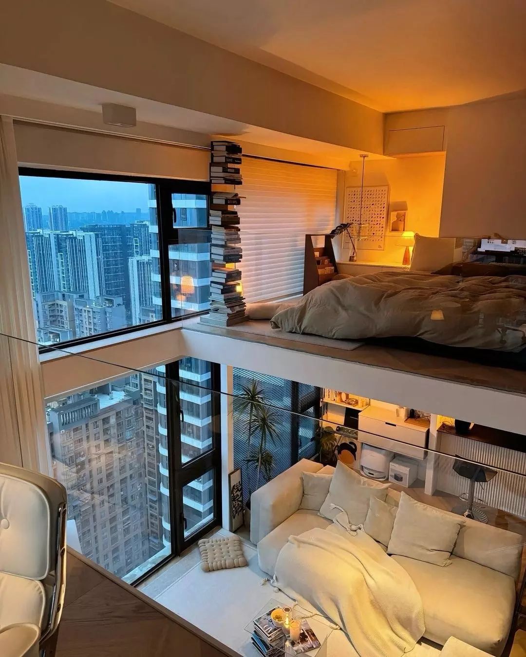 A modern high-rise apartment bedroom with a stack of books by the window