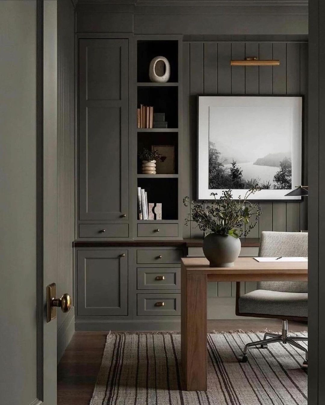 A sleek home office with dark gray built-ins and modern decor