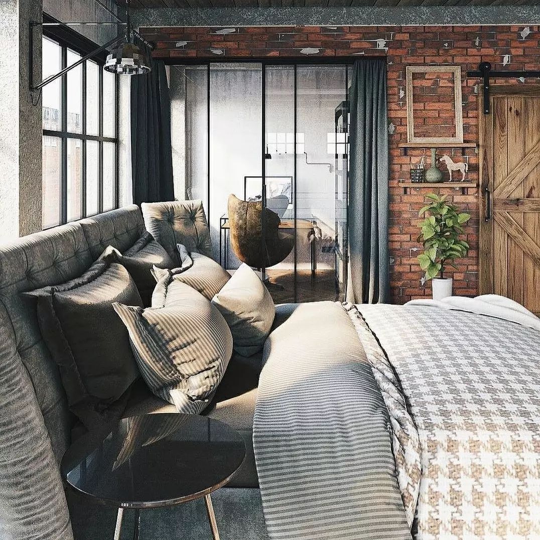 A modern industrial-style bedroom with exposed brick walls and a sliding barn door