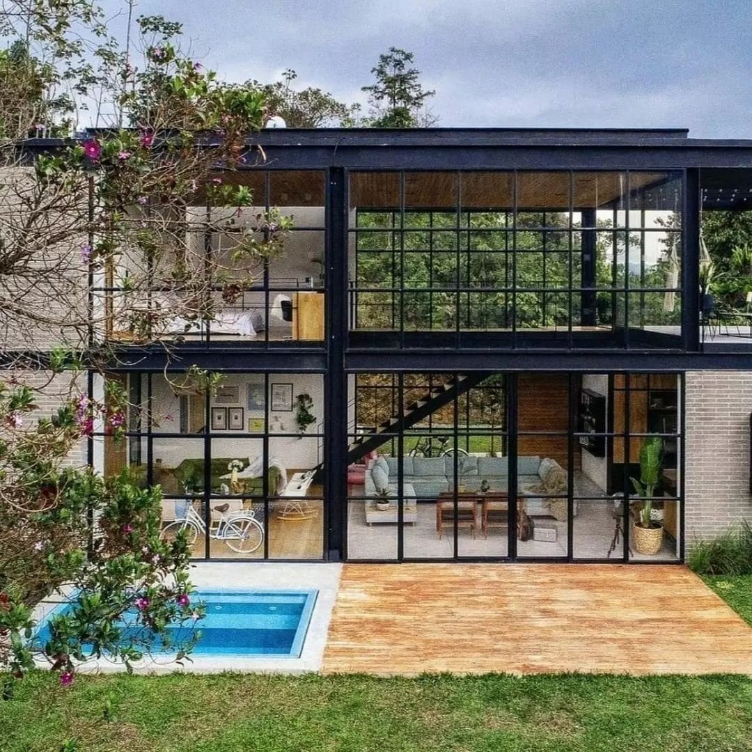 A modern two-story home featuring large glass windows and an industrial design