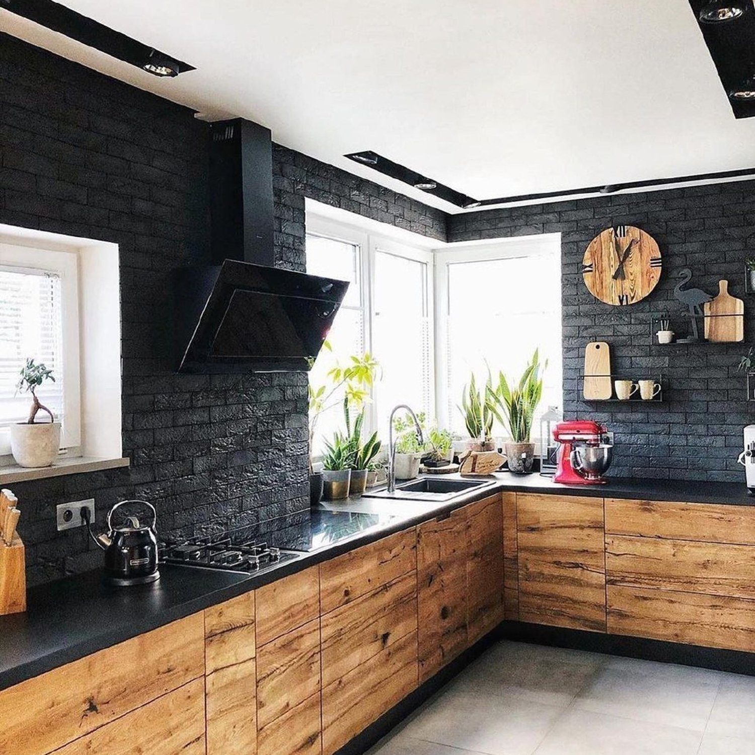 Stylish and modern kitchen with black brick walls, natural wood cabinets and stainless steel appliances