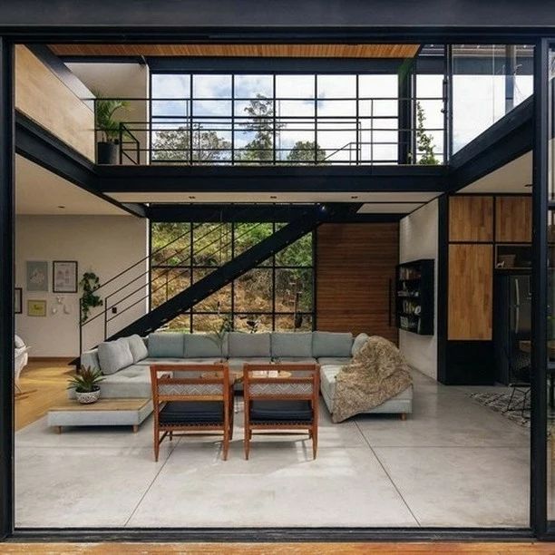 A modern industrial living room with large glass panes