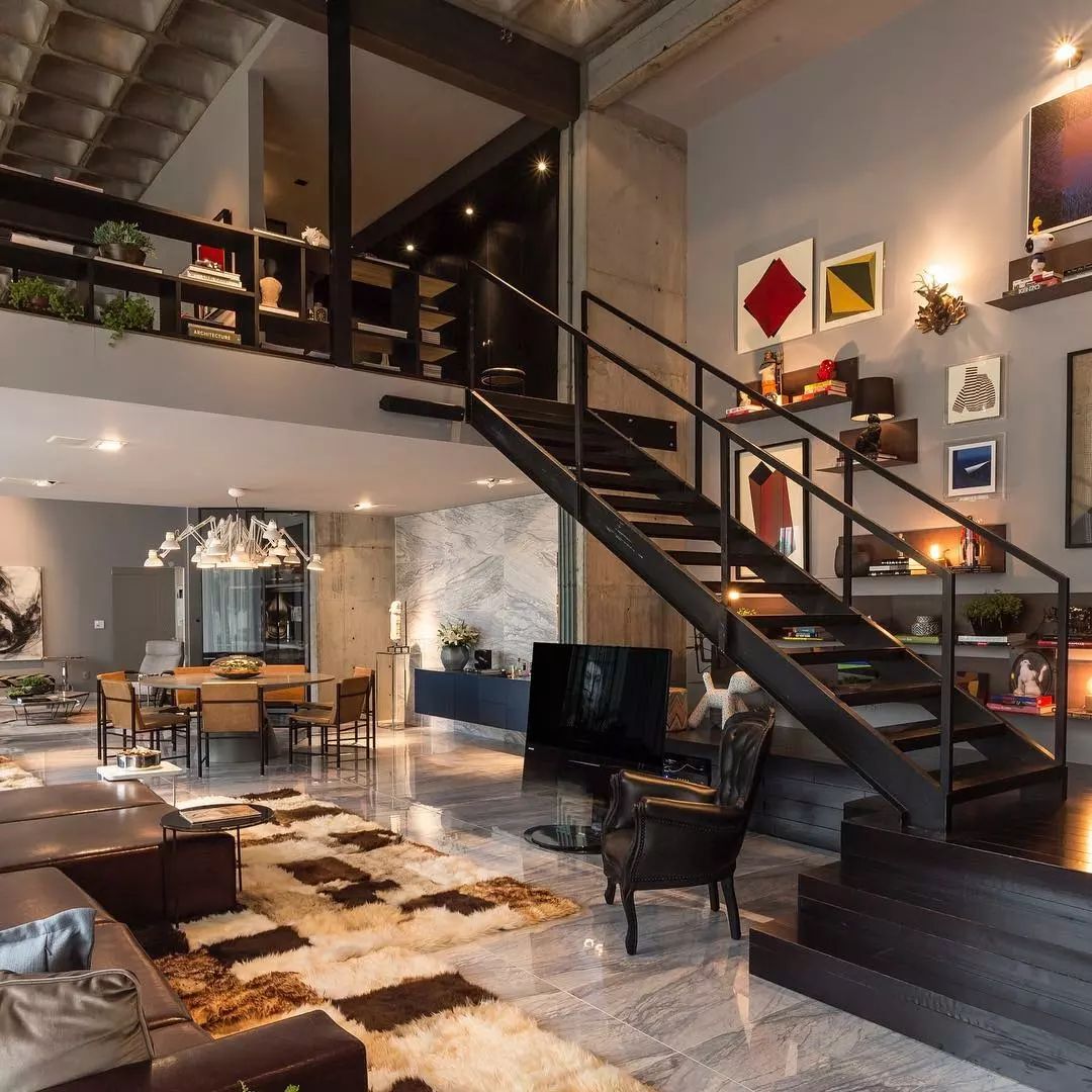 A chic modern loft with an industrial touch featuring exposed concrete, a striking black staircase, and stylish eclectic decor.