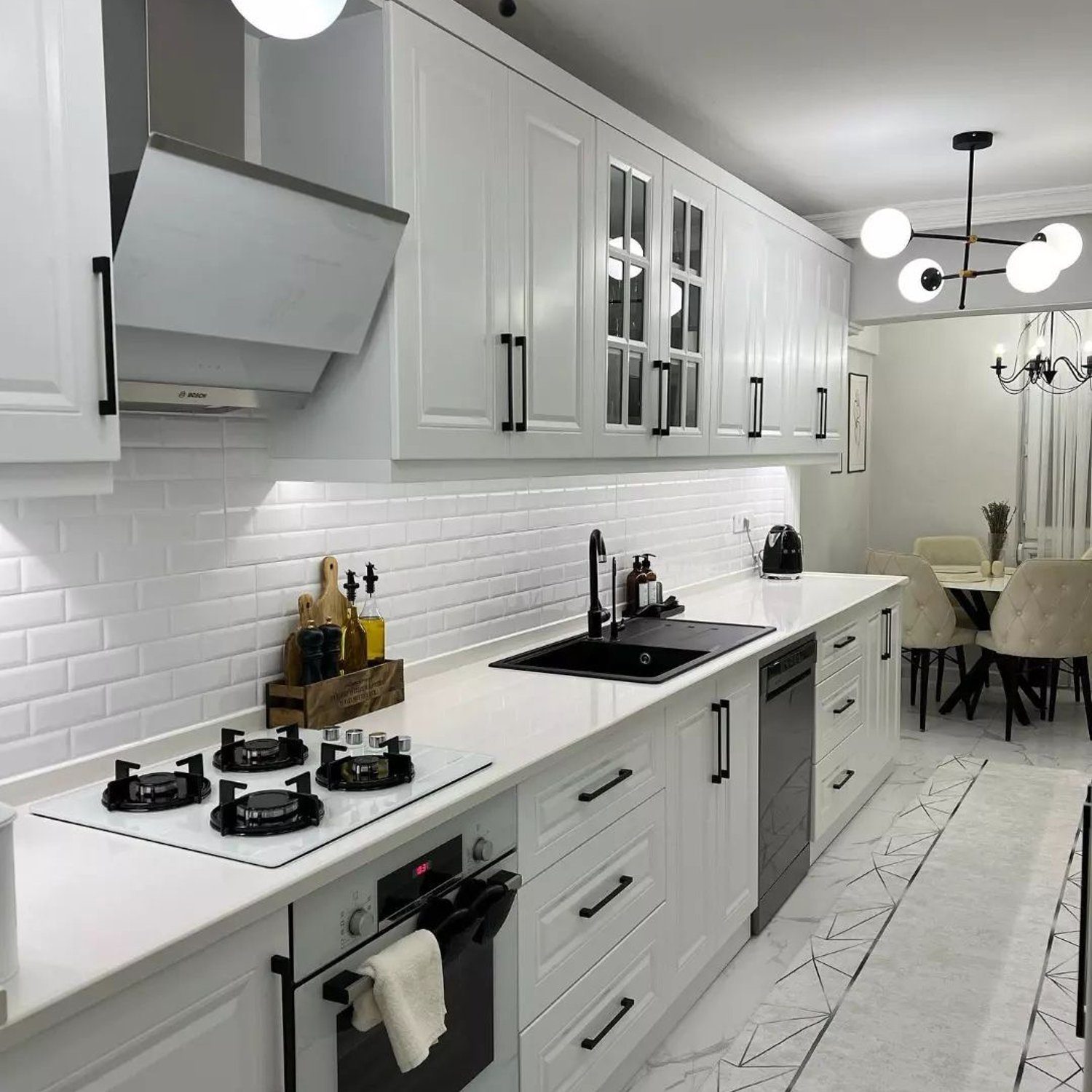 A modern kitchen with white cabinetry and subway tile backsplash