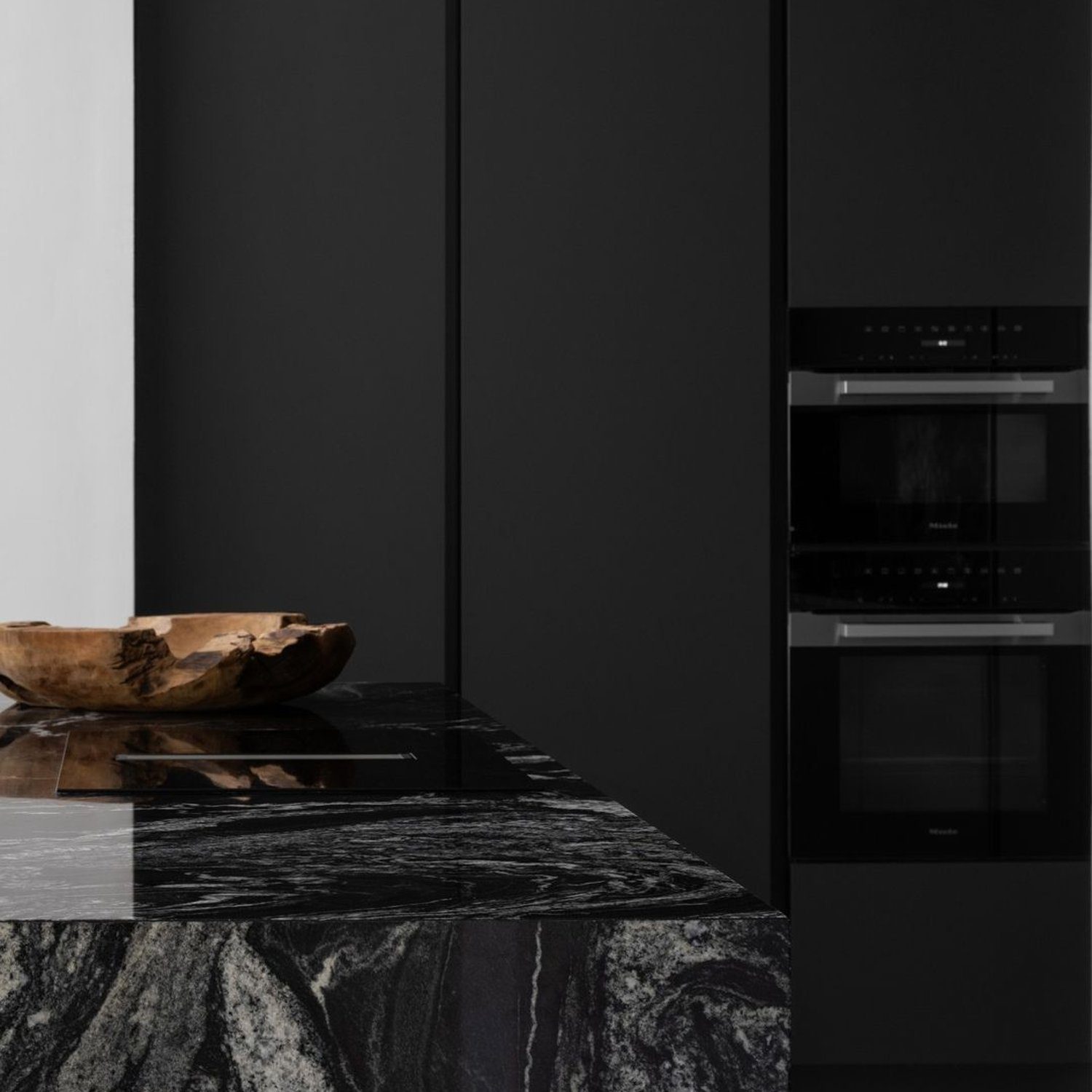 A sleek, modern kitchen featuring an elegant marble island and monochromatic cabinetry