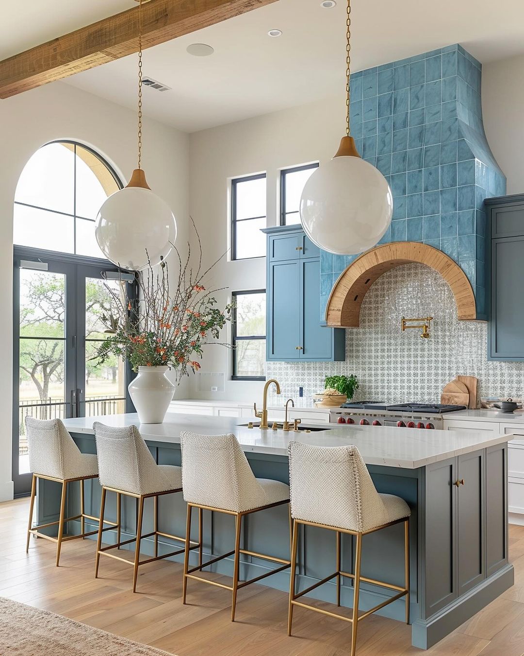 A modern kitchen featuring blue cabinetry, brass accents, and a unique arched cooking alcove