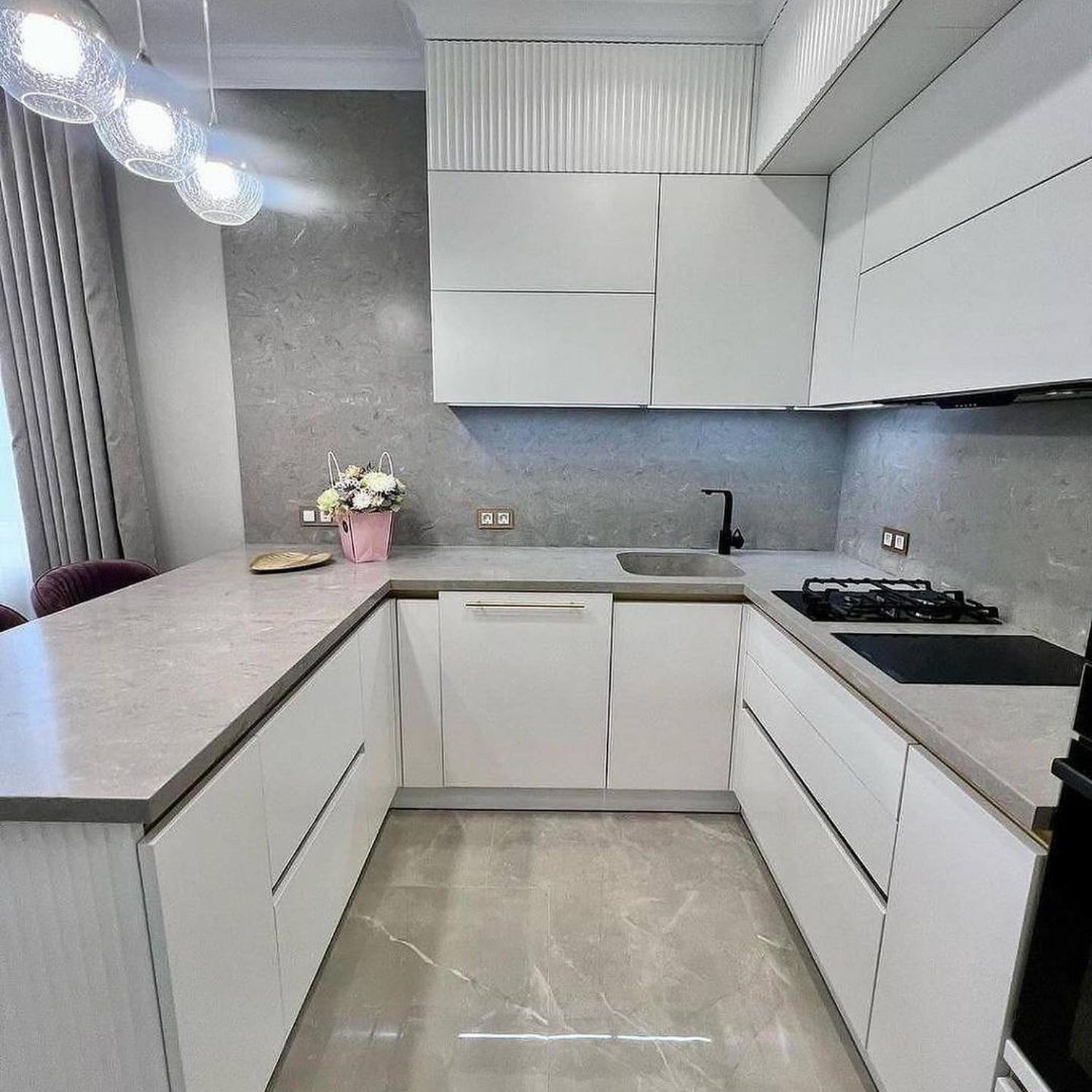 A sleek and modern kitchen with high-gloss white cabinets, matte grey backsplash, and minimalist design