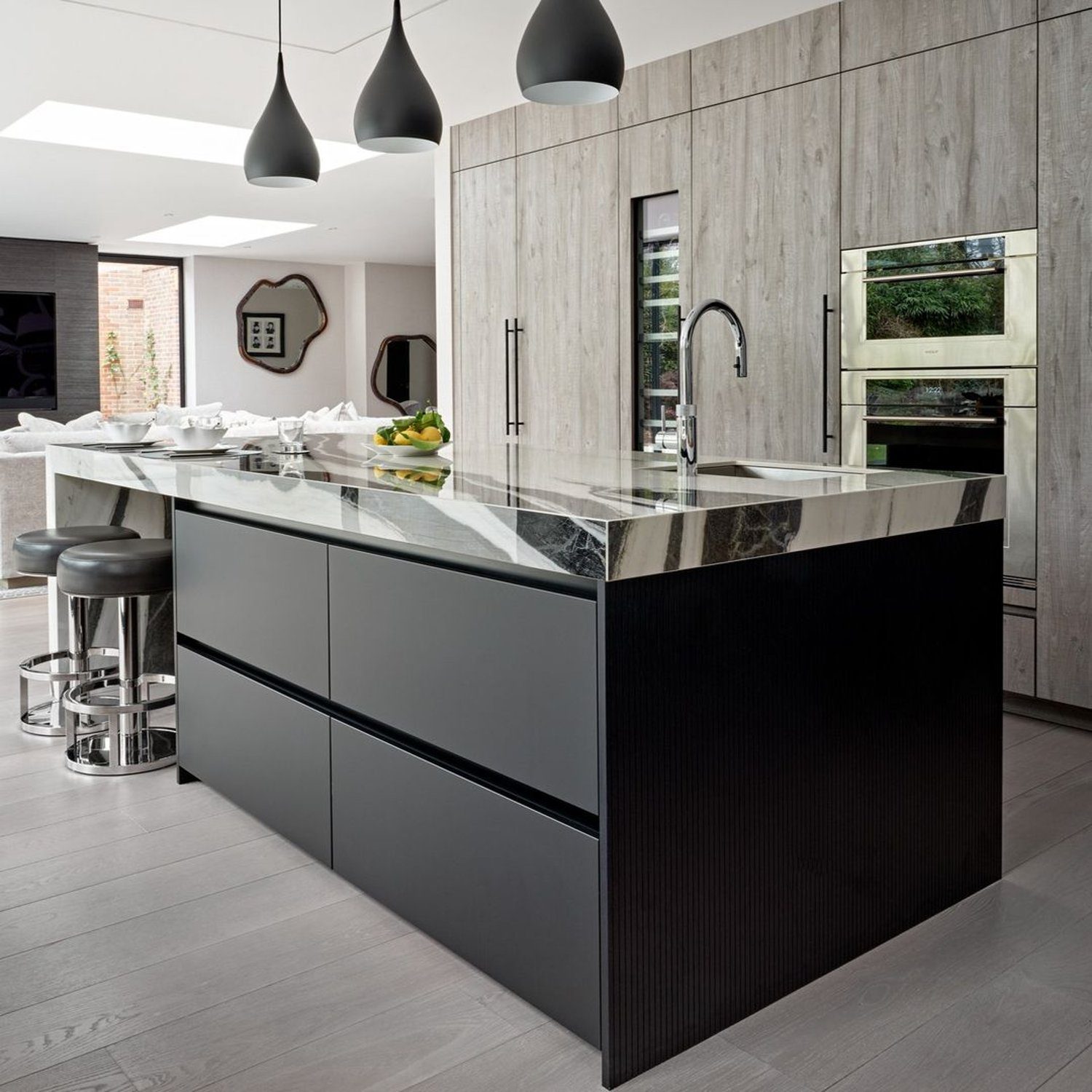 A sleek and modern kitchen featuring a central island with a polished black marble countertop, stylish pendant lights, and state-of-the-art appliances