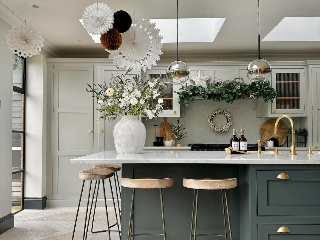 A modern kitchen with dark green cabinetry and gold hardware