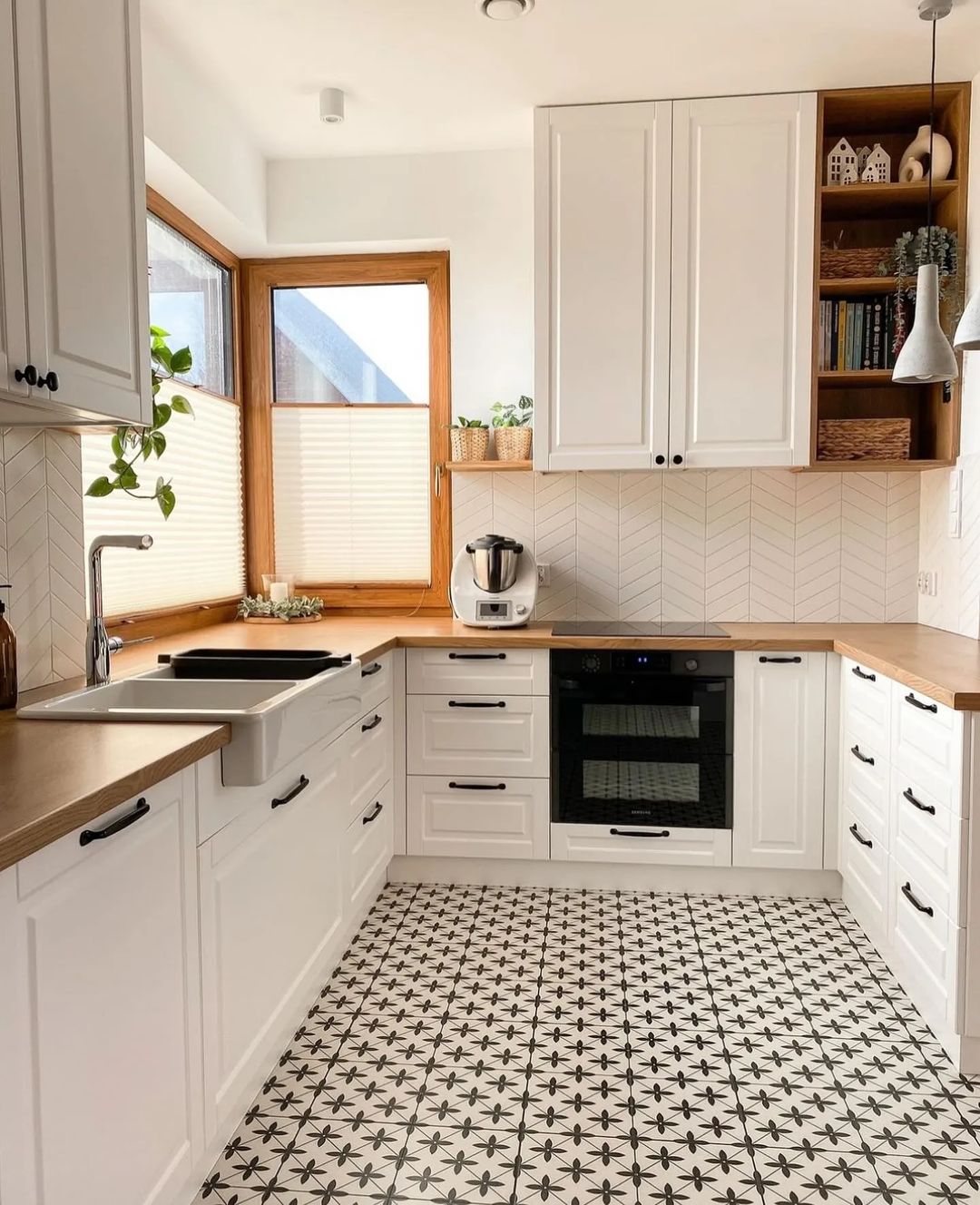 A modern kitchen with geometric-patterned floor tiles and white cabinetry.