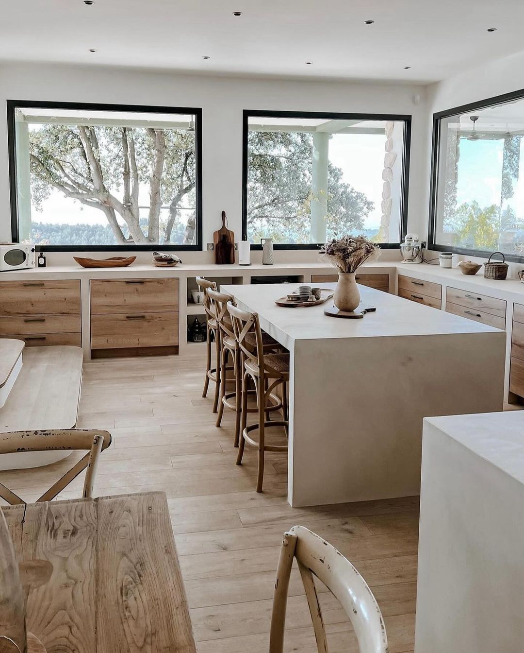 A modern kitchen space with warm wood accents and large windows