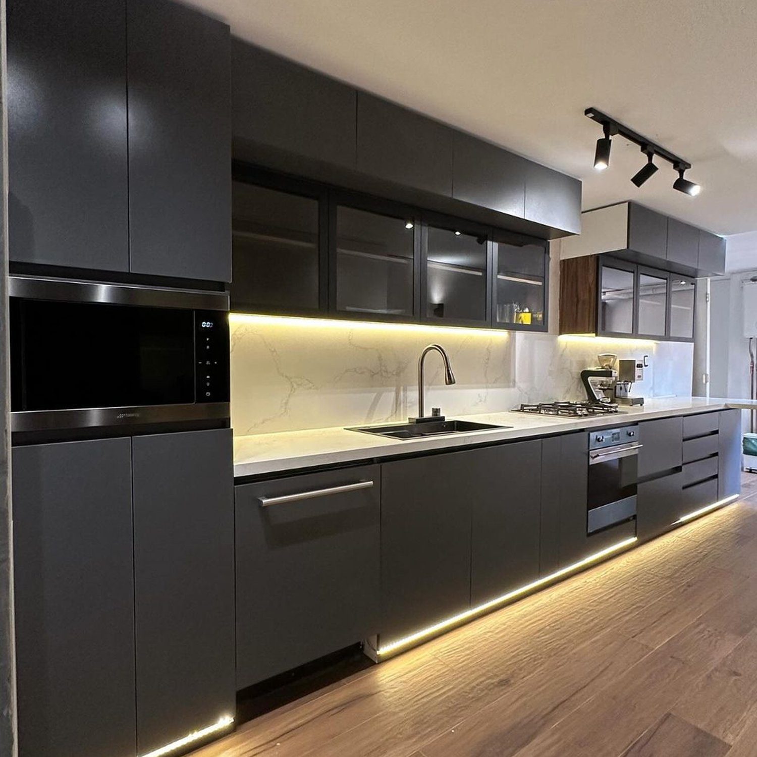 A sleek and modern kitchen illuminated by under-cabinet and toe-kick lighting