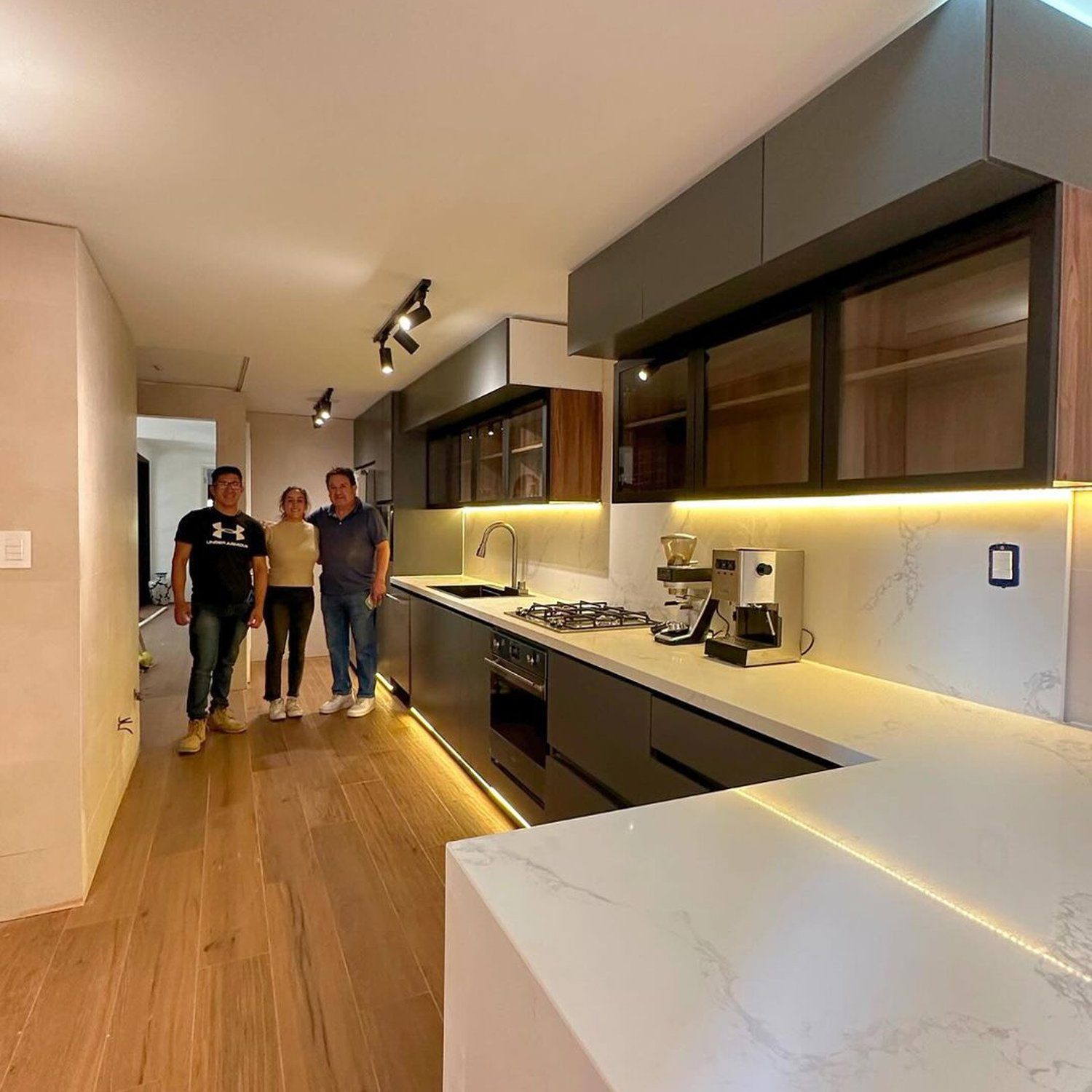 A modern kitchen featuring sharp lines, a harmonious blend of wooden textures and sleek grey cabinetry.