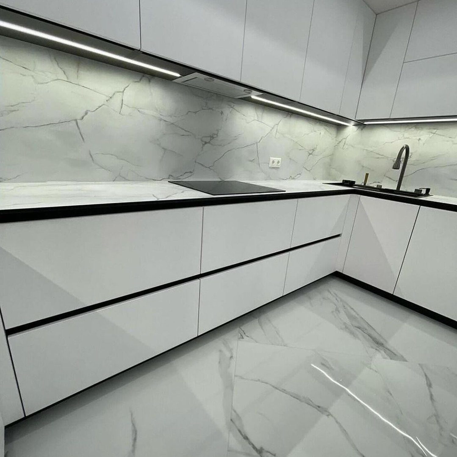 A sleek and modern kitchen featuring high-gloss white cabinetry and marble-patterned surfaces