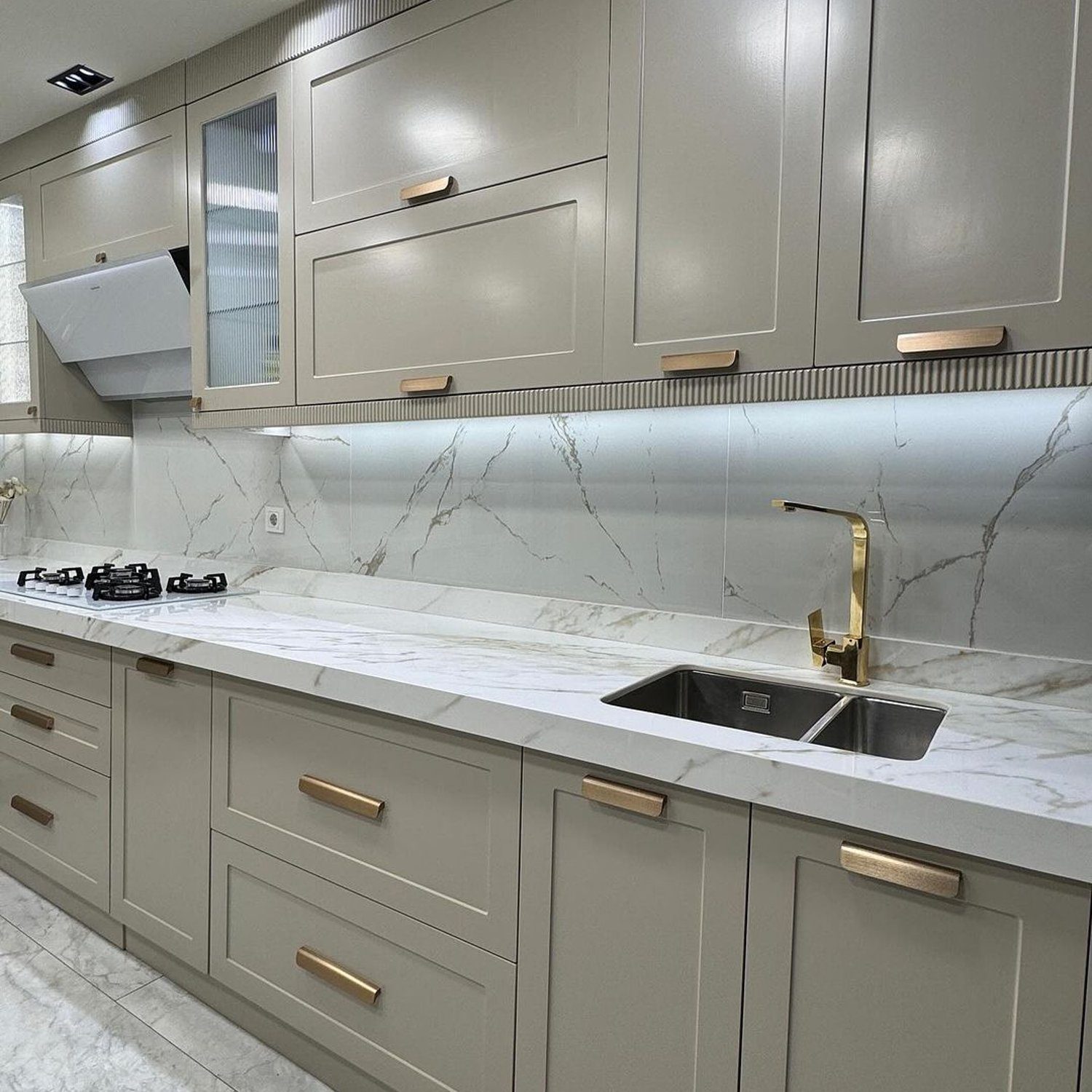 A sleek modern kitchen with marble backsplash and gold accents