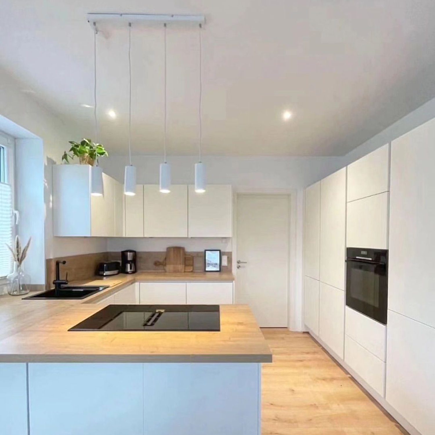 A sleek and modern kitchen design with white cabinetry and wooden accents.