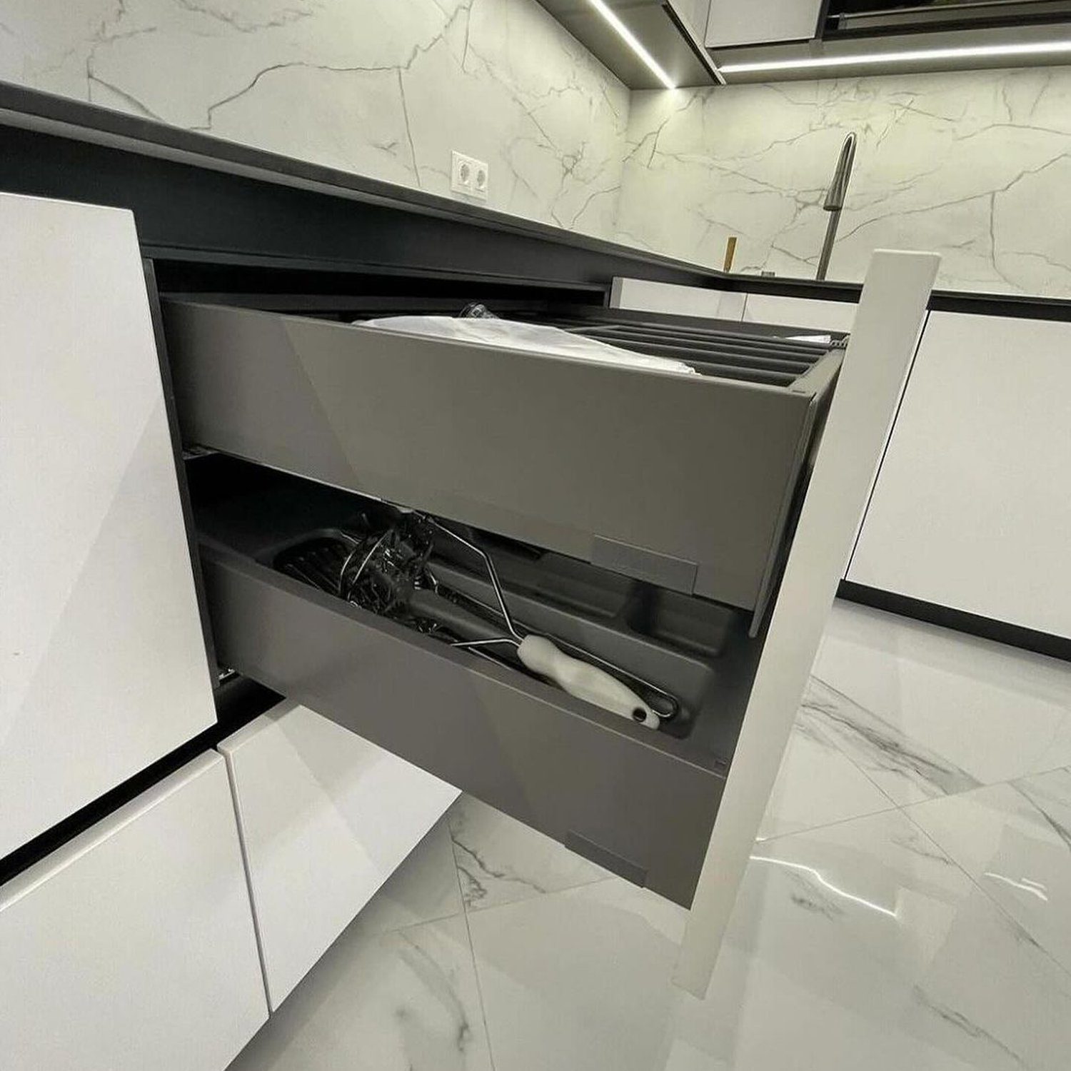 A modern kitchen drawer partially open, revealing neatly organized utensils