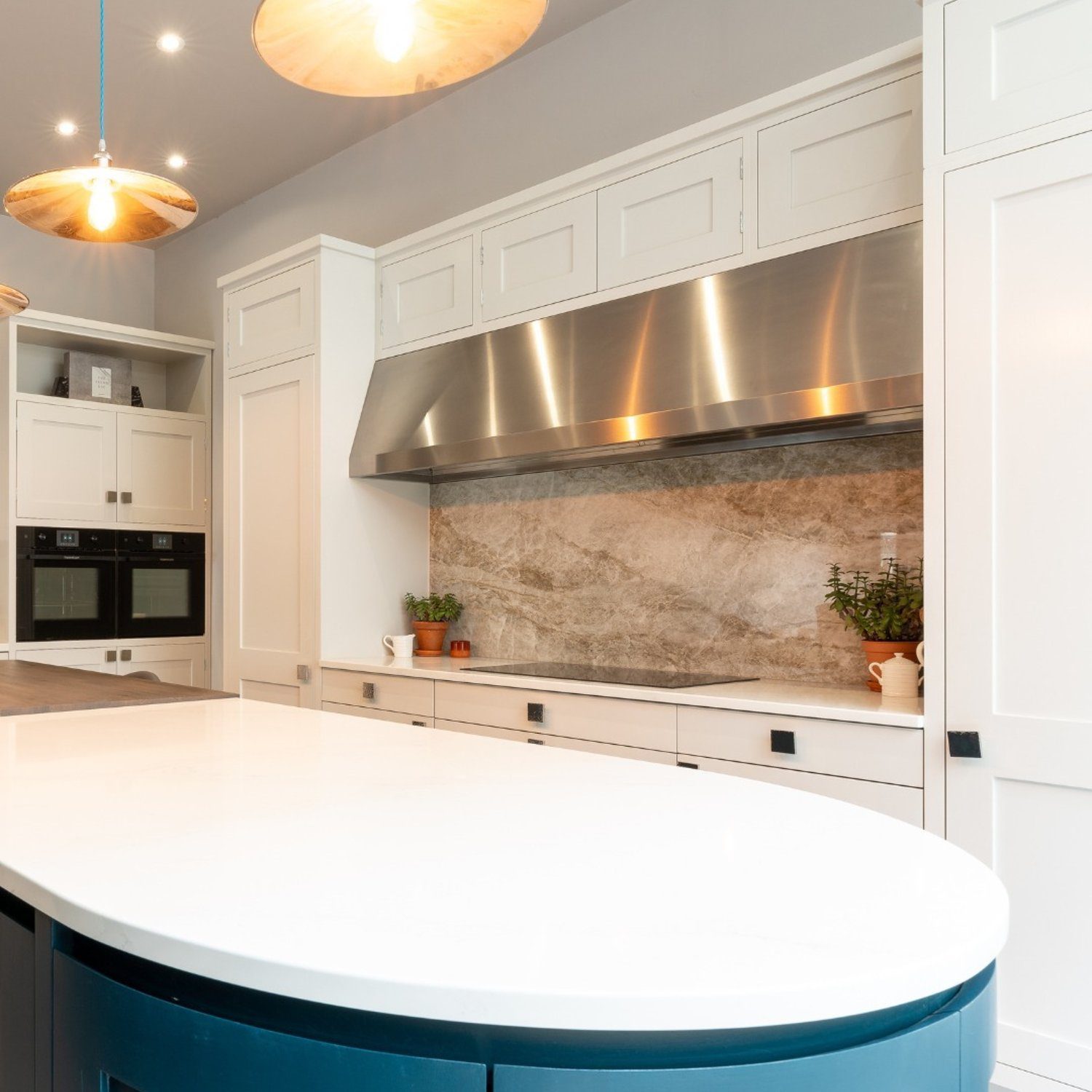 A modern kitchen featuring a curved blue island and marble accents