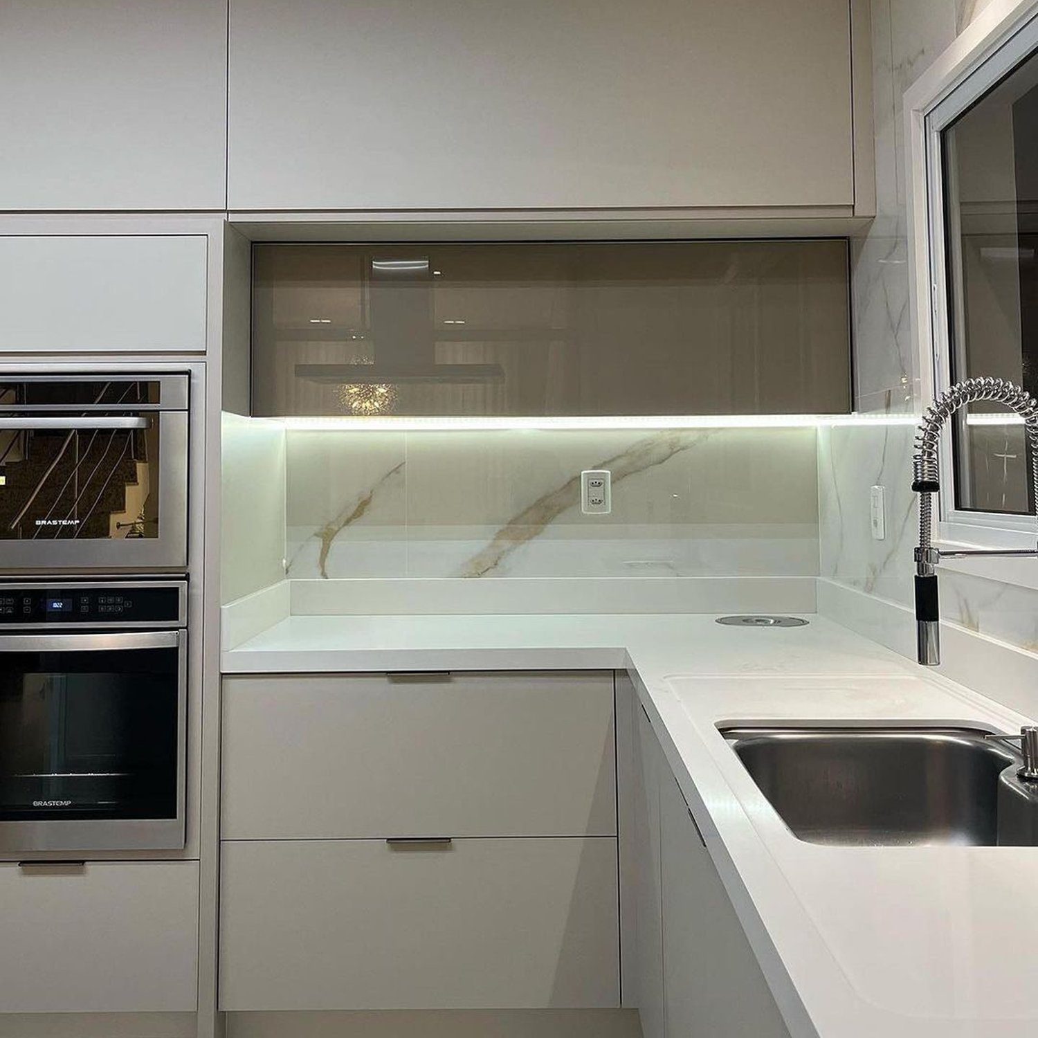 A modern kitchen featuring sleek white cabinetry and marble backsplash