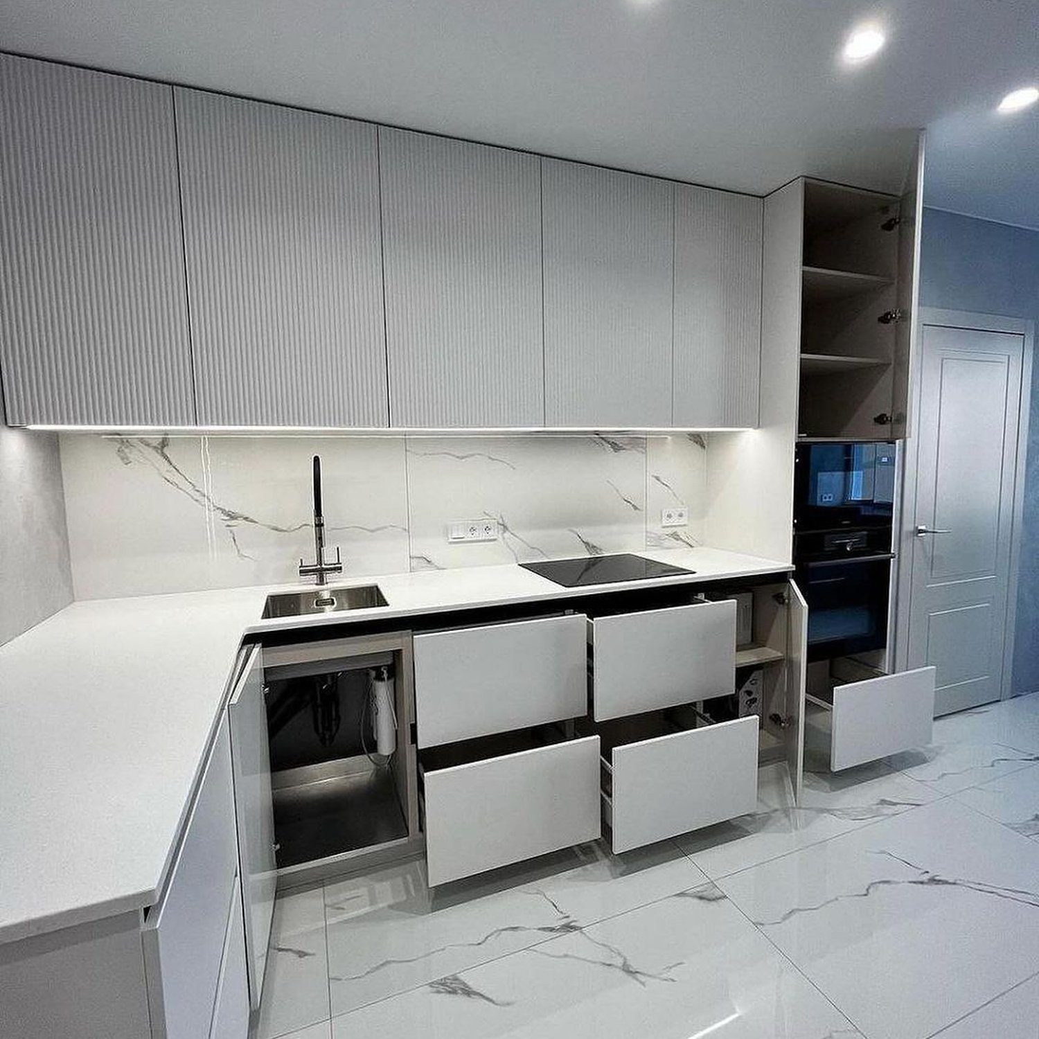 Sleek and modern kitchen design with glossy white cabinetry and marble accents.