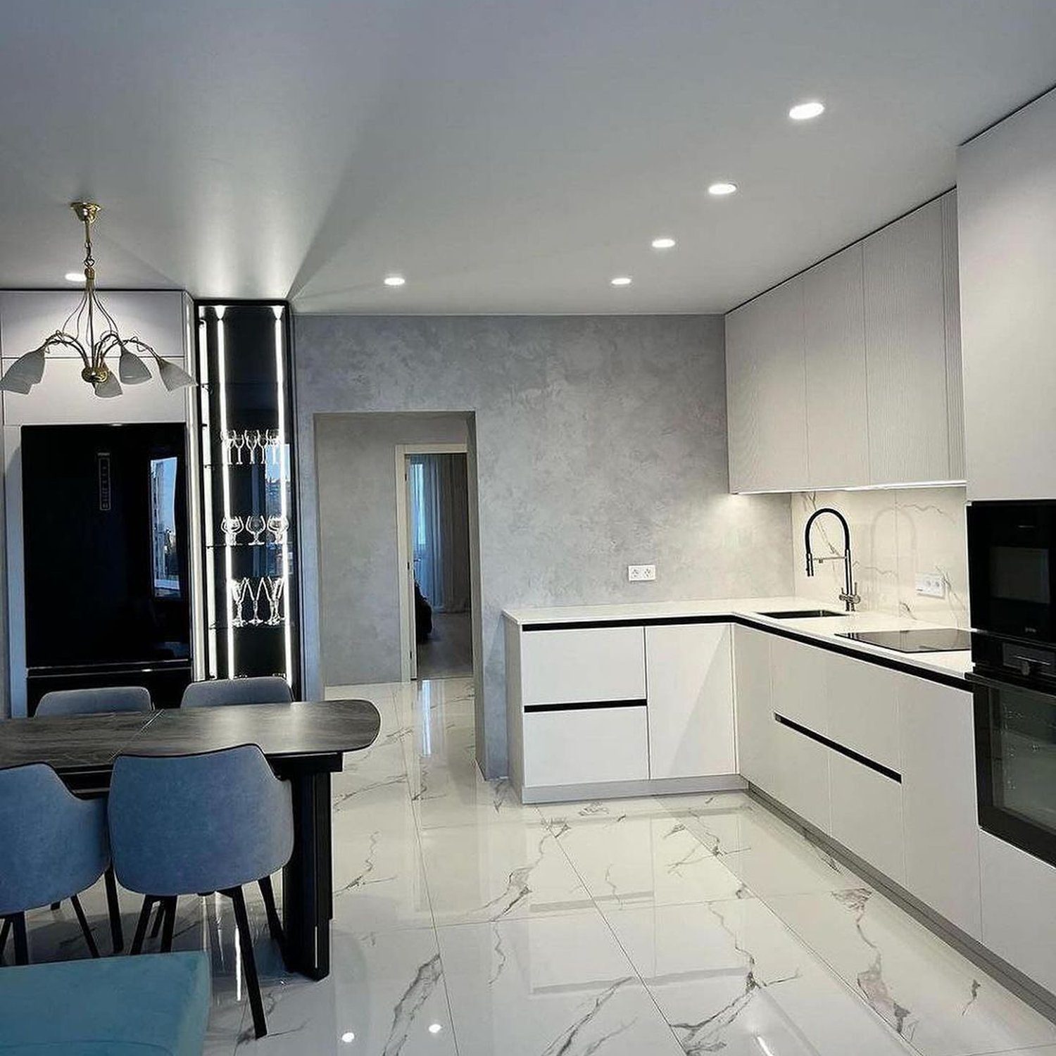 A sleek and modern kitchen featuring marble flooring, clean-lined white cabinetry, and contemporary lighting fixtures