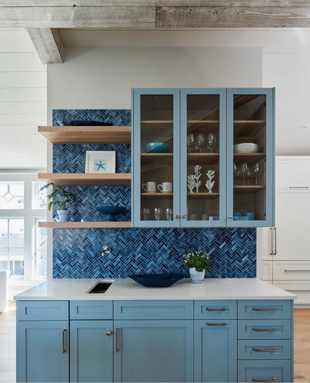 A thoughtfully designed kitchen with blue cabinetry and geometric backsplash