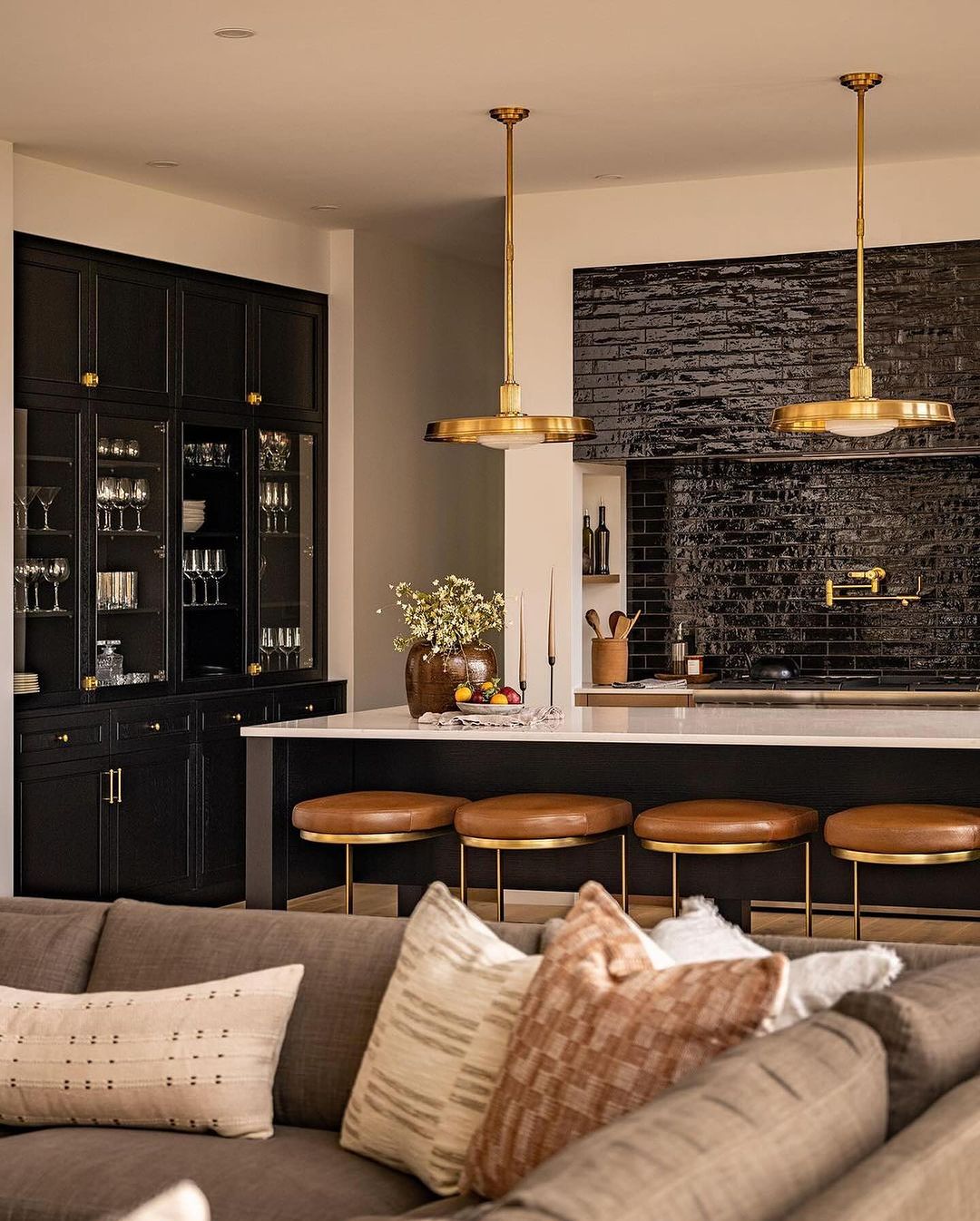 A modern kitchen with dark cabinets and brass accents