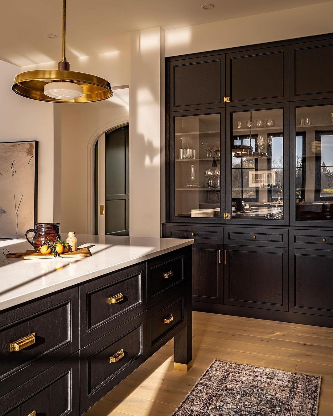 A sophisticated kitchen featuring deep-toned cabinetry and modern brass hardware