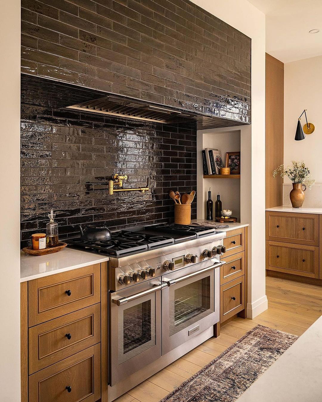 A chic modern kitchen featuring dark glazed brick backsplash and gold fixtures