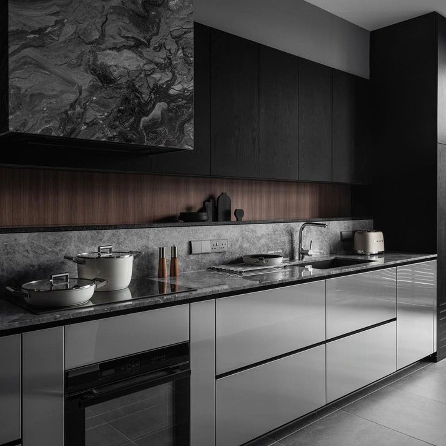 A sleek and modern kitchen design featuring dark wood cabinetry, stainless steel appliances, and a marble backsplash.