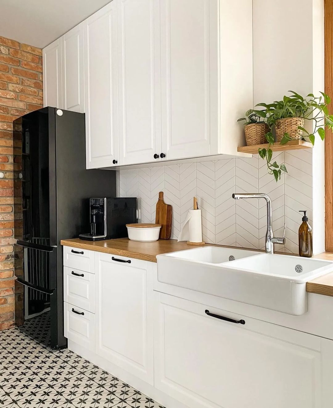 A chic modern kitchen featuring exposed brickwork, patterned floor tiles, and sleek white cabinetry