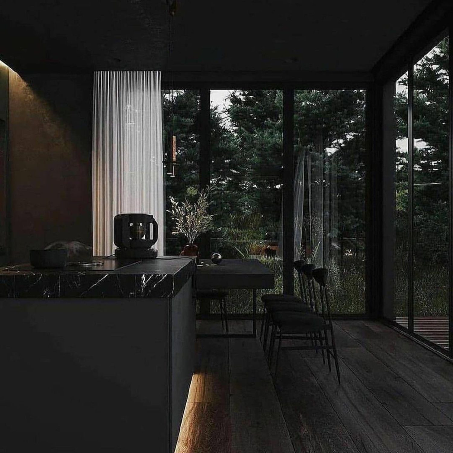 A modern kitchen with large windows offering a forest view