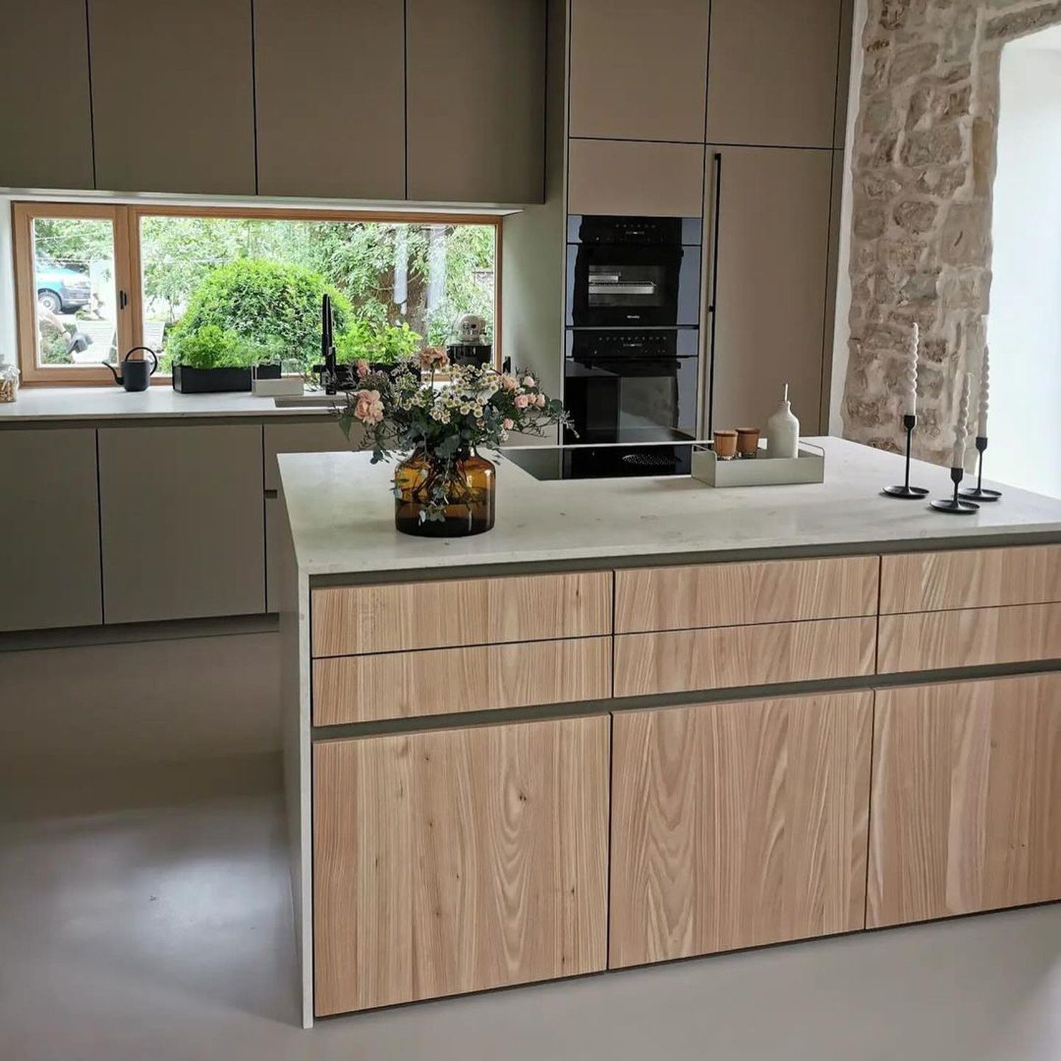 A sleek modern kitchen with integrated appliances and a stone accent wall