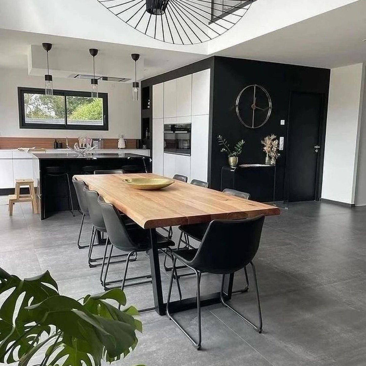 A sleek and modern kitchen featuring a unique pendant light and a live-edge dining table.