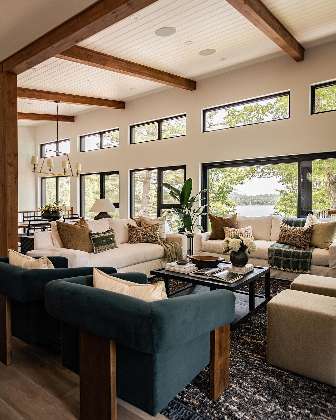 A modern, cozy lakeside living room with expansive windows and vaulted ceilings