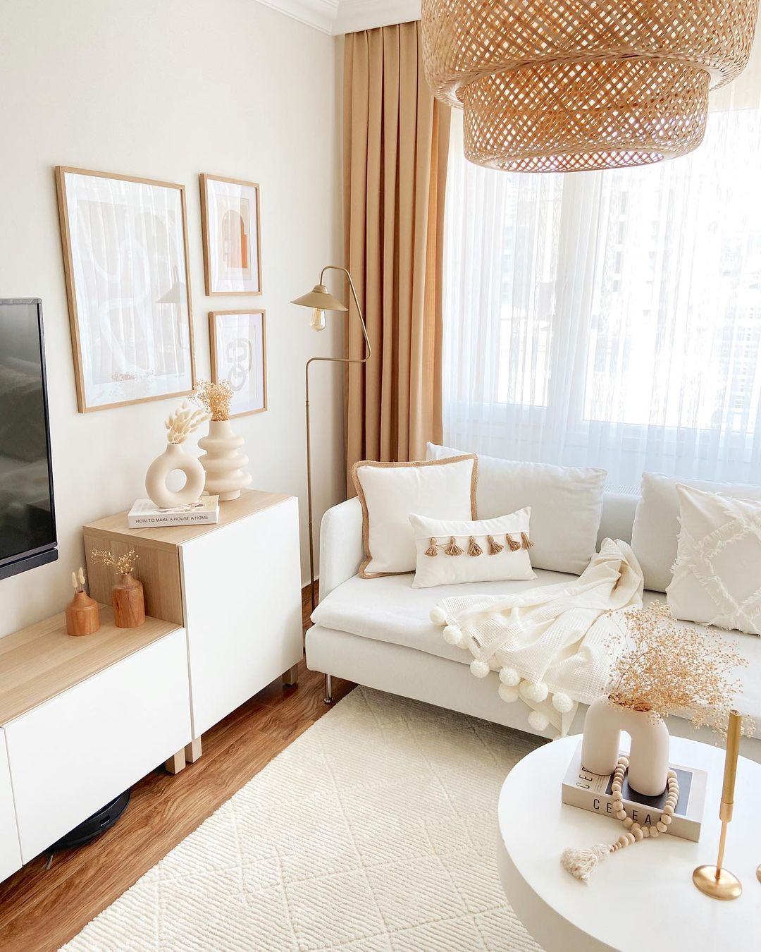 A chic and modern living room featuring a beige sofa adorned with textured throw pillows, a stylish rattan pendant light, and minimalist artwork