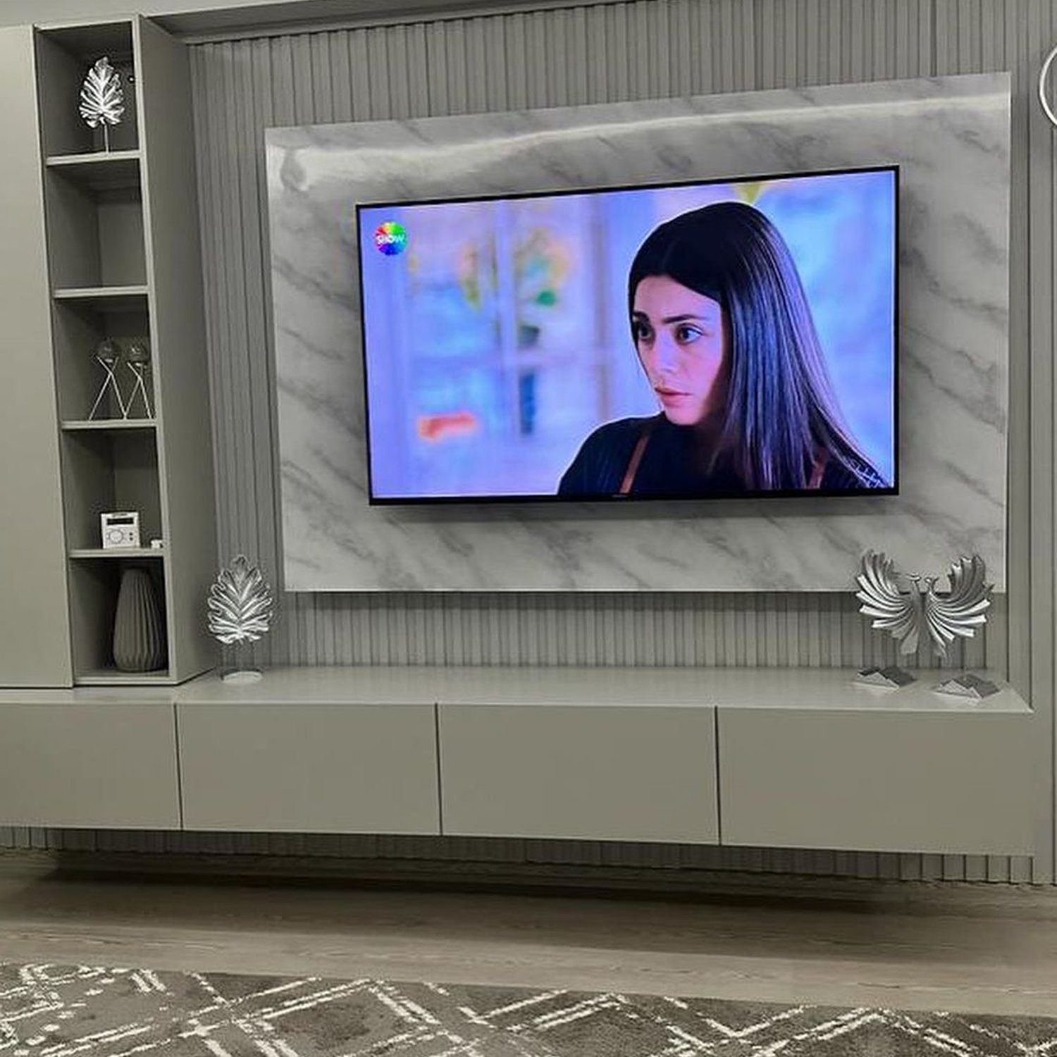 A modern living room with a wall-mounted television displaying an on-screen character