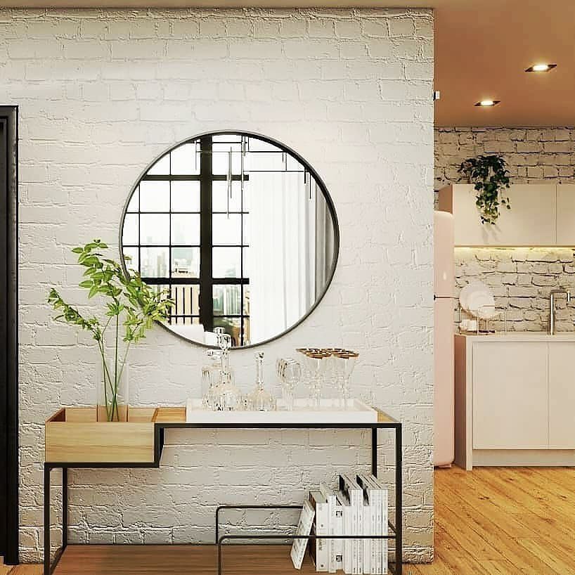 A chic modern living room featuring a white brick wall with a large round mirror, reflecting a window pane