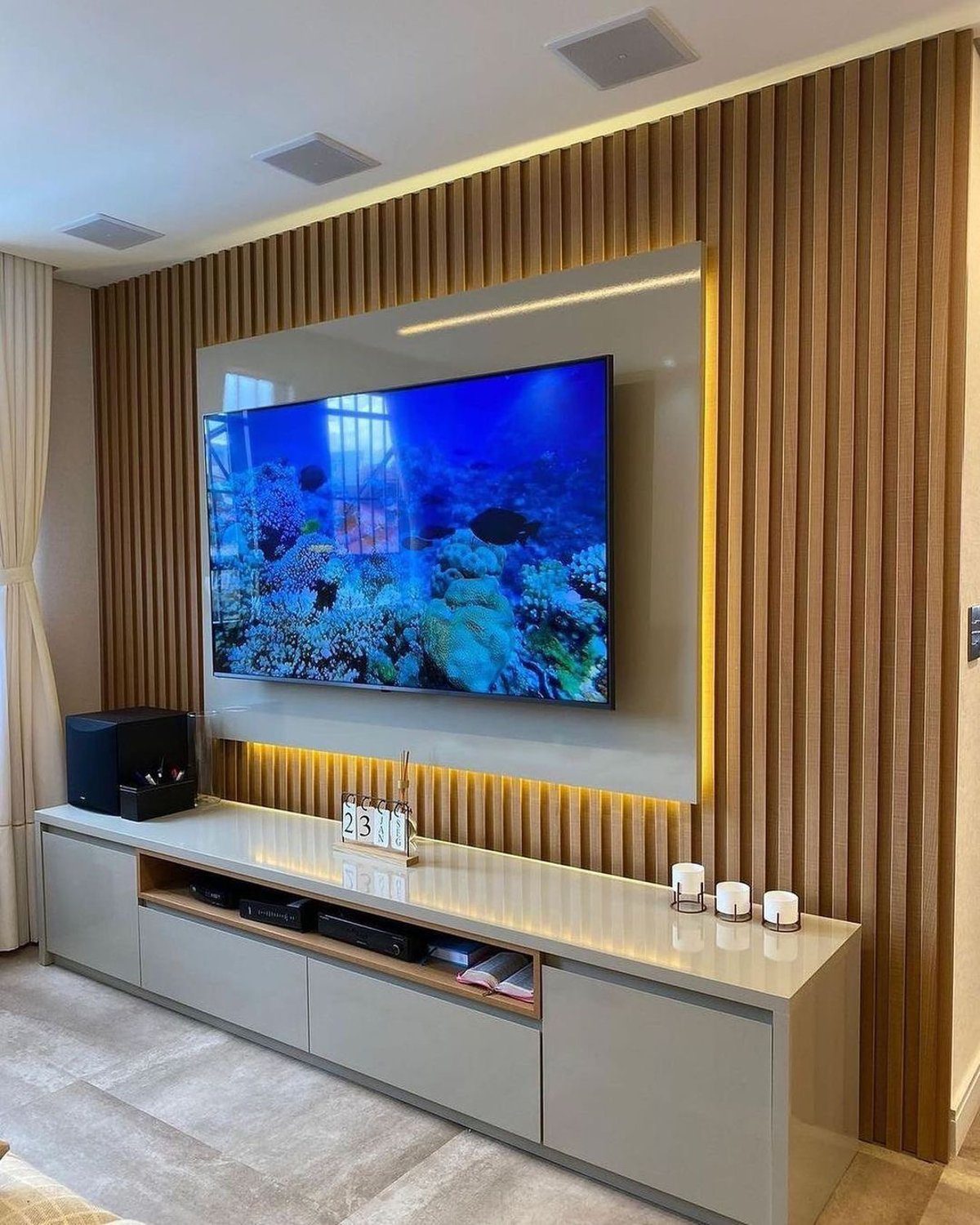 A sleek and modern living room featuring a large wall-mounted TV surrounded by a warm wooden paneling