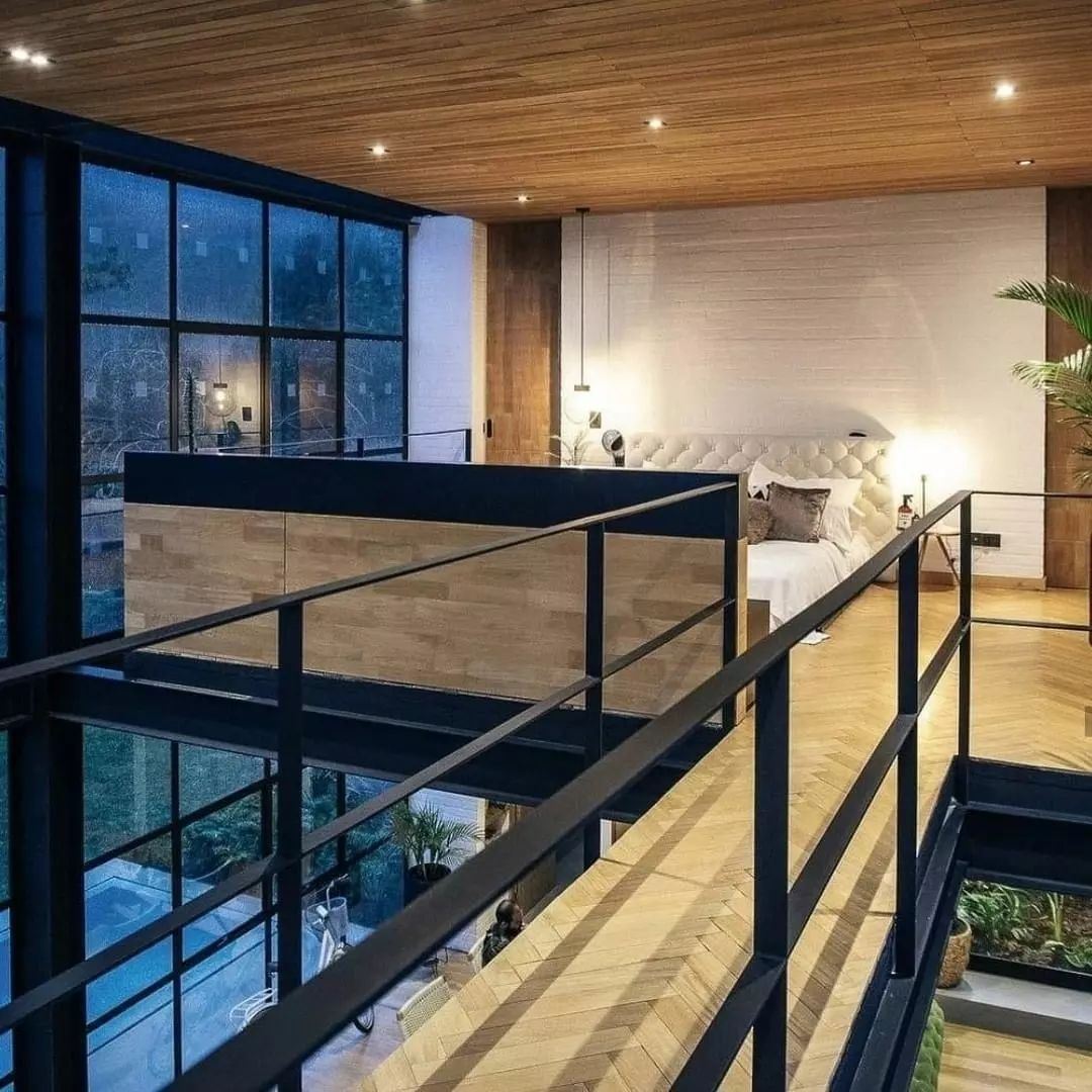 A modern loft bedroom with expansive windows and a cozy bed