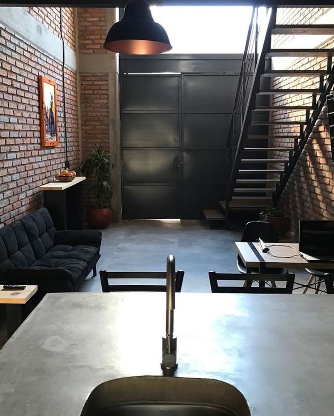 A modern loft space featuring exposed brick walls and a metal staircase