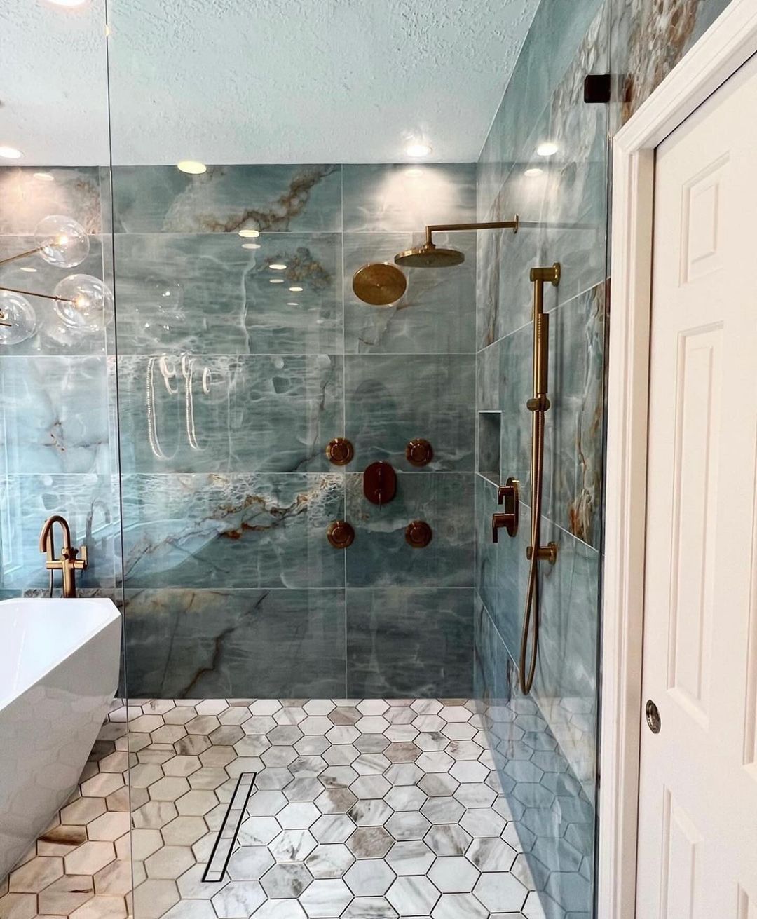 A modern bathroom featuring unique marble patterns and bronze fixtures