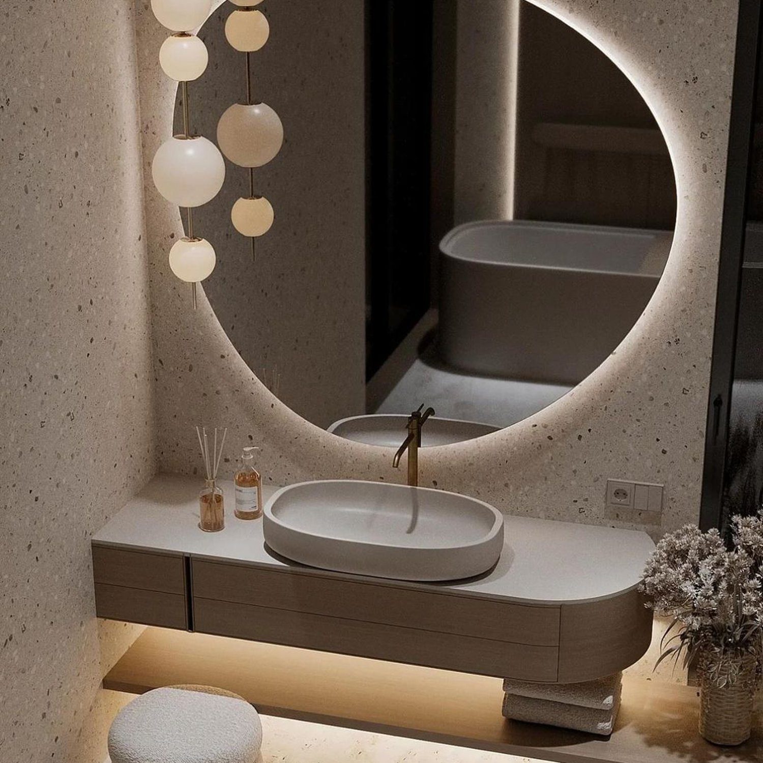 A modern minimalist bathroom featuring a circular illuminated mirror and an elegant floating vanity