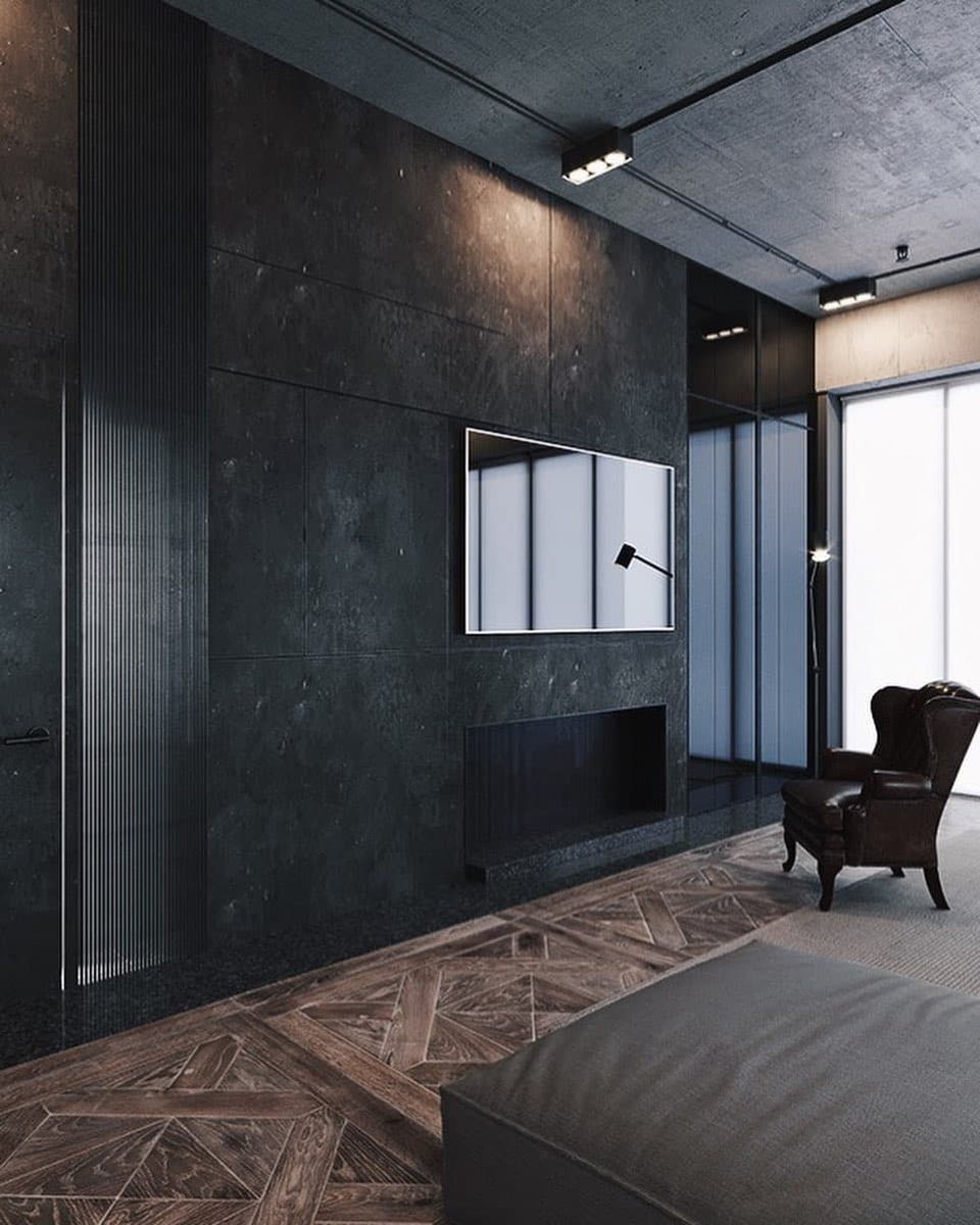 A modern minimalist bedroom with a herringbone wood floor, exposed concrete walls, and a sleek mounted television