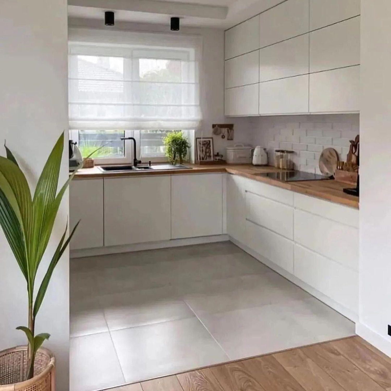 A minimalist kitchen with sleek white cabinetry and a wooden countertop