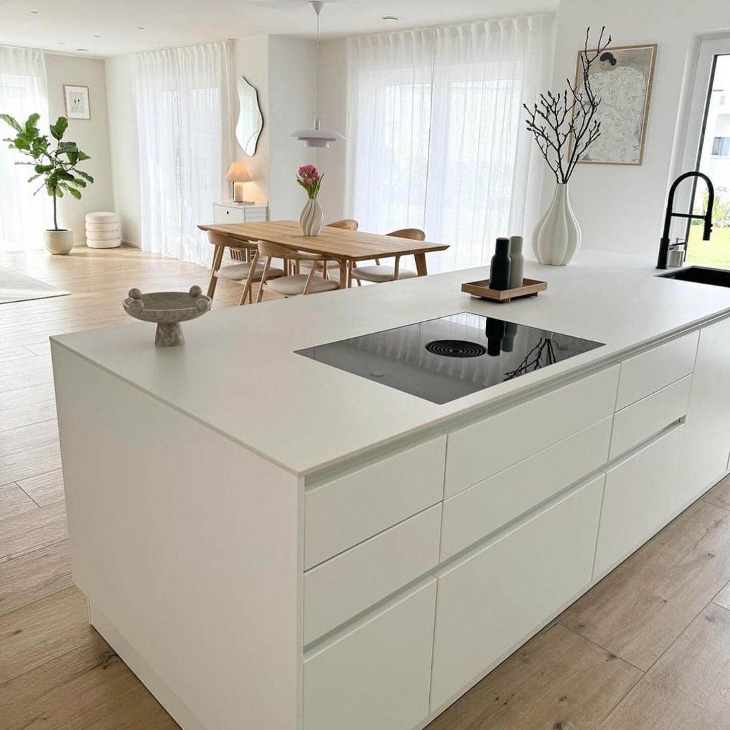 A minimalist kitchen design featuring a central island with a built-in cooktop