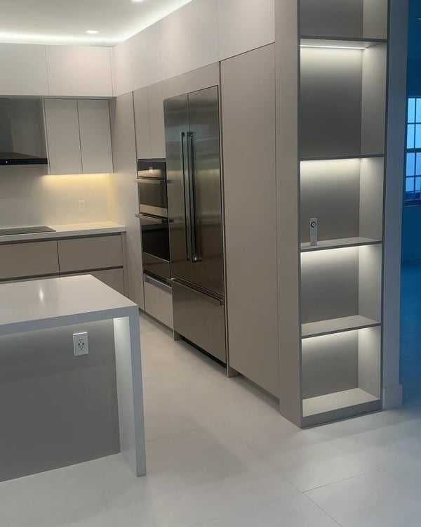 A sleek and modern kitchen featuring integrated stainless steel appliances, recessed lighting, and minimalist grey cabinetry.