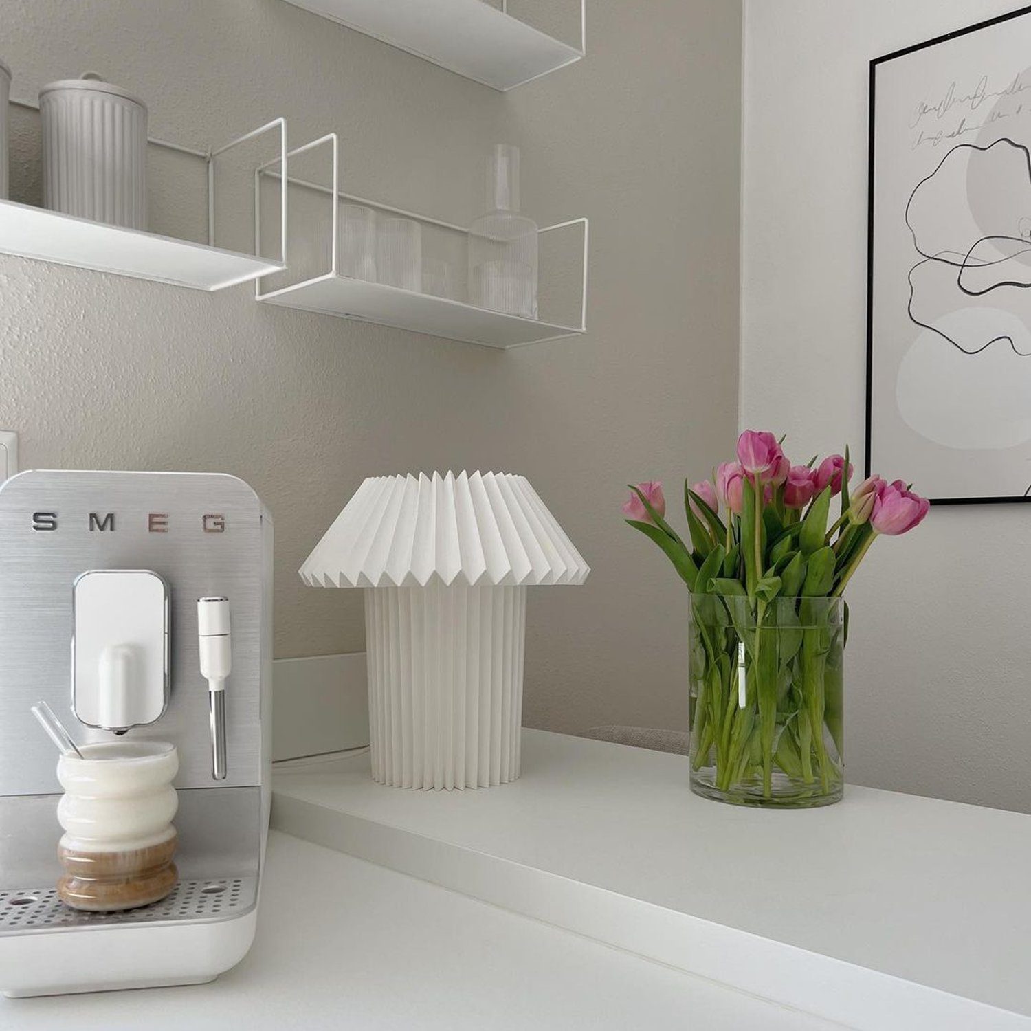 A minimalist kitchen corner featuring modern appliances and fresh tulips