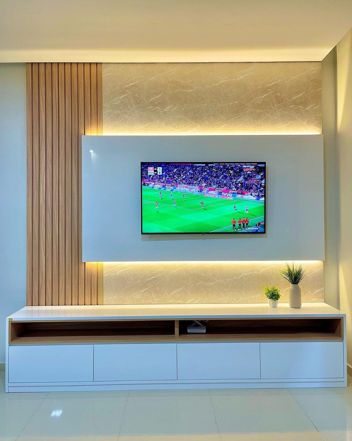 A modern, minimalist living room with a mounted TV displaying a sports game